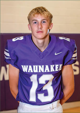 A young man wearing a white and black jersey with the number 14 on it. Description generated by AI