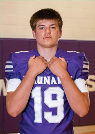 A young man wearing a white and black jersey with the number 14 on it. Description generated by AI