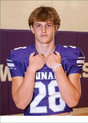 A young man wearing a white and black jersey with the number 14 on it. Description generated by AI