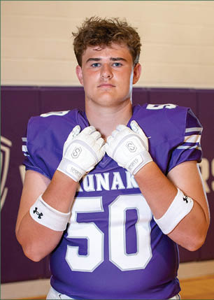 A young man wearing a white and black jersey with the number 14 on it. Description generated by AI