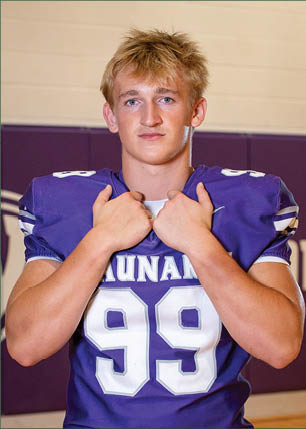 A young man wearing a white and black jersey with the number 14 on it. Description generated by AI