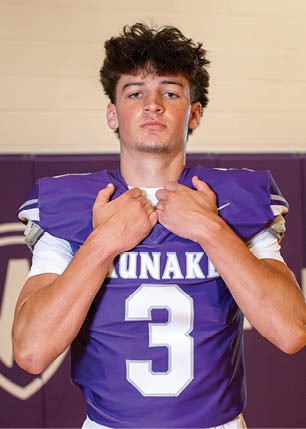 A young man wearing a white and black jersey with the number 14 on it. Description generated by AI