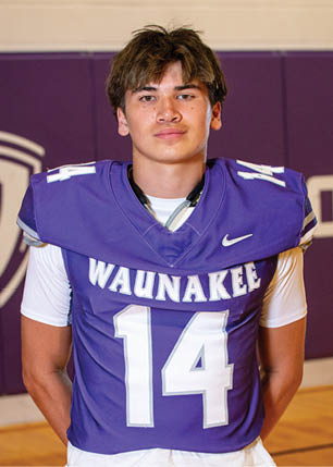 A young man wearing a white and black jersey with the number 14 on it. Description generated by AI