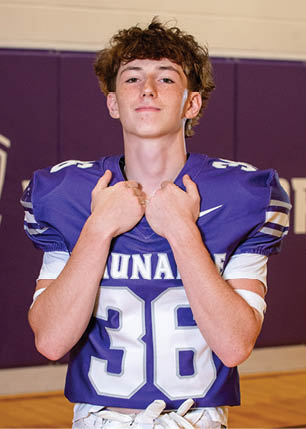 A young man wearing a white and black jersey with the number 14 on it. Description generated by AI