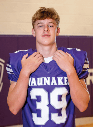 A young man wearing a white and black jersey with the number 14 on it. Description generated by AI