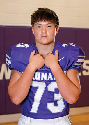 A young man wearing a white and black jersey with the number 14 on it. Description generated by AI