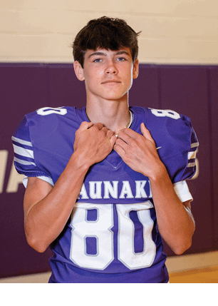 A young man wearing a white and black jersey with the number 14 on it. Description generated by AI