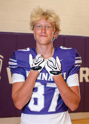 A young man wearing a white and black jersey with the number 14 on it. Description generated by AI