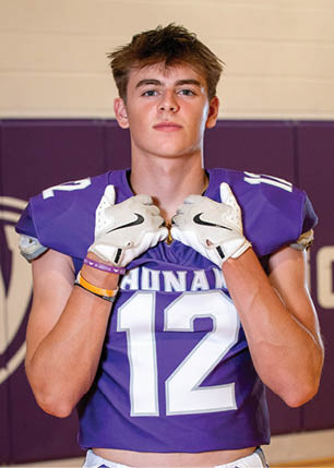 A young man wearing a white and black jersey with the number 14 on it. Description generated by AI