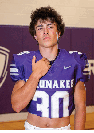 A young man wearing a white and black jersey with the number 14 on it. Description generated by AI