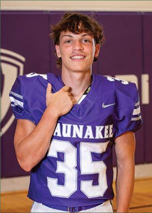 A young man wearing a white and black jersey with the number 14 on it. Description generated by AI