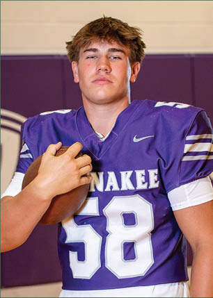 A young man wearing a white and black jersey with the number 14 on it. Description generated by AI