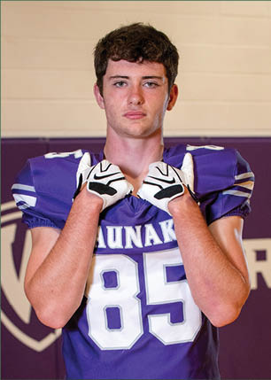 A young man wearing a white and black jersey with the number 14 on it. Description generated by AI