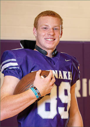 A young man wearing a white and black jersey with the number 14 on it. Description generated by AI