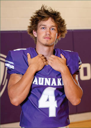 A young man wearing a white and black jersey with the number 14 on it. Description generated by AI