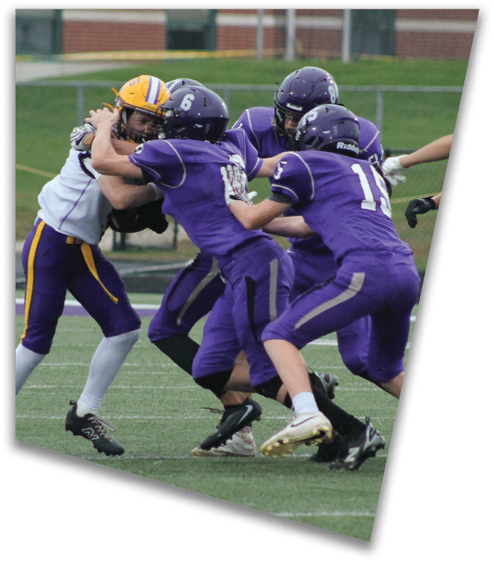 A person wearing a dark football uniform and helmet with “American Canyon" on the jersey is kneeling on one knee on a field at night. Description generated by AI