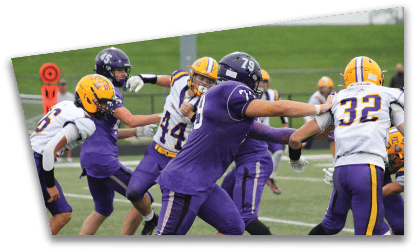 People wearing black American Canyon football uniforms and helmets are standing on a football field at night. Description generated by AI