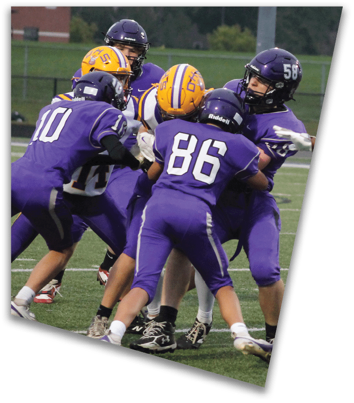 A person wearing a dark football uniform and helmet with “American Canyon" on the jersey is kneeling on one knee on a field at night. Description generated by AI