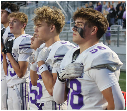 A group of football players huddled together on the field. Description generated by AI