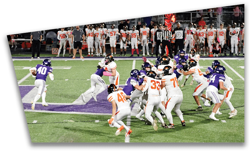 People wearing black American Canyon football uniforms and helmets are standing on a football field at night. Description generated by AI