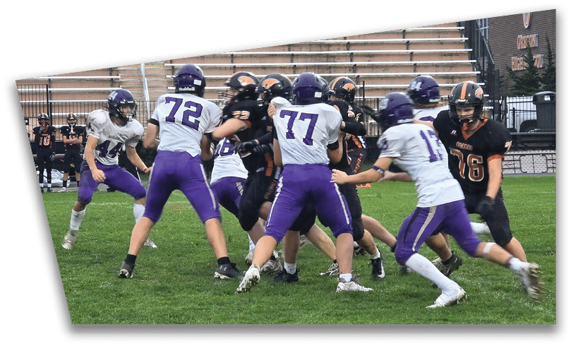 People wearing black American Canyon football uniforms and helmets are standing on a football field at night. Description generated by AI