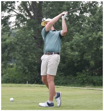 Two adults are on a golf course with one swinging a golf club and the other standing nearby holding a golf club. Description generated by AI