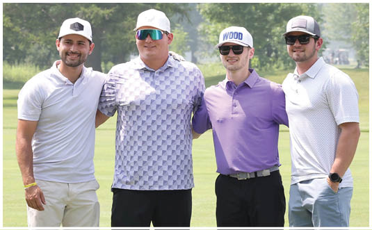 Three adults wearing sunglasses and casual golf attire stand closely together outdoors on a sunny day with a grassy background. Description generated by AI
