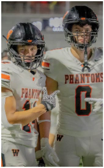 Two football players wearing blue and white uniforms. Description generated by AI