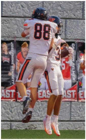 Two football players wearing blue and white uniforms. Description generated by AI
