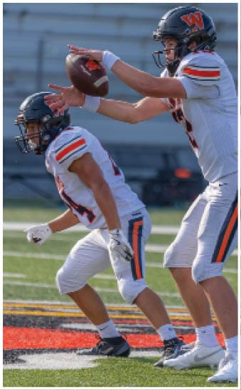 Two football players wearing blue and white uniforms. Description generated by AI
