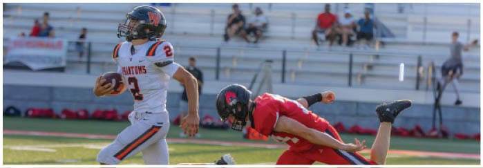 A football game is taking place on a field with players wearing blue and white uniforms. Description generated by AI