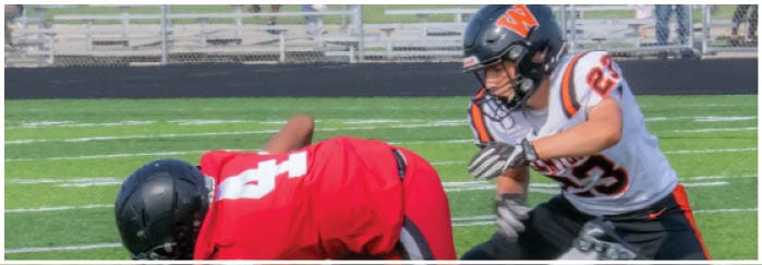 A football game is taking place on a field with players wearing blue and white uniforms. Description generated by AI