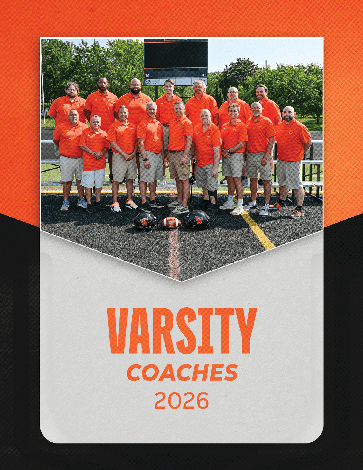 A group of people wearing matching orange shirts and khaki shorts stand on a sports field with football helmets and a football placed in front of them, with the text “VARSITY COACHES 2026" below. Description generated by AI