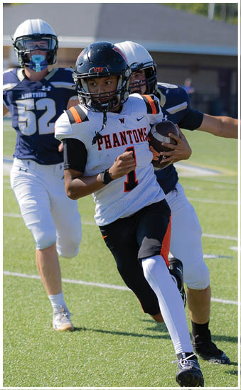 A person wearing a sports uniform is extending their arm forward while standing on a green football field. Description generated by AI