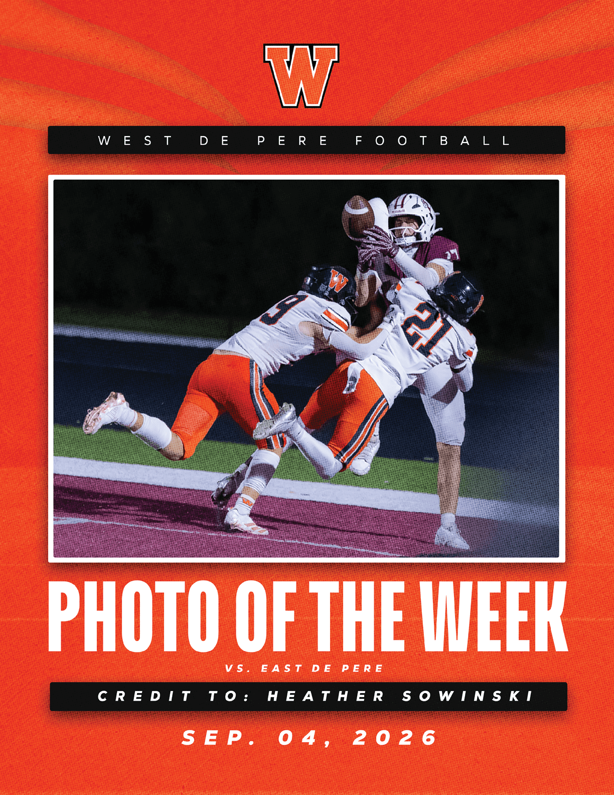 Three football players in action with two players in white and orange uniforms attempting to tackle a player in a white and maroon uniform catching a football on a field. Description generated by AI