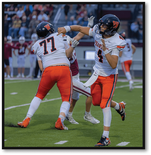 People wearing orange and white sports uniforms are playing football on a green field. Description generated by AI
