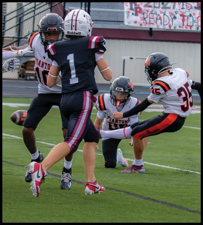 People in football uniforms are actively engaged in a play on a green field with a football in mid-air. Description generated by AI
