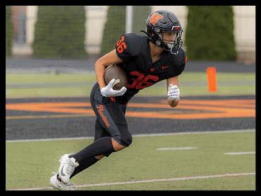 A person wearing a black football uniform with the number 36 is running on a field while holding a football. Description generated by AI