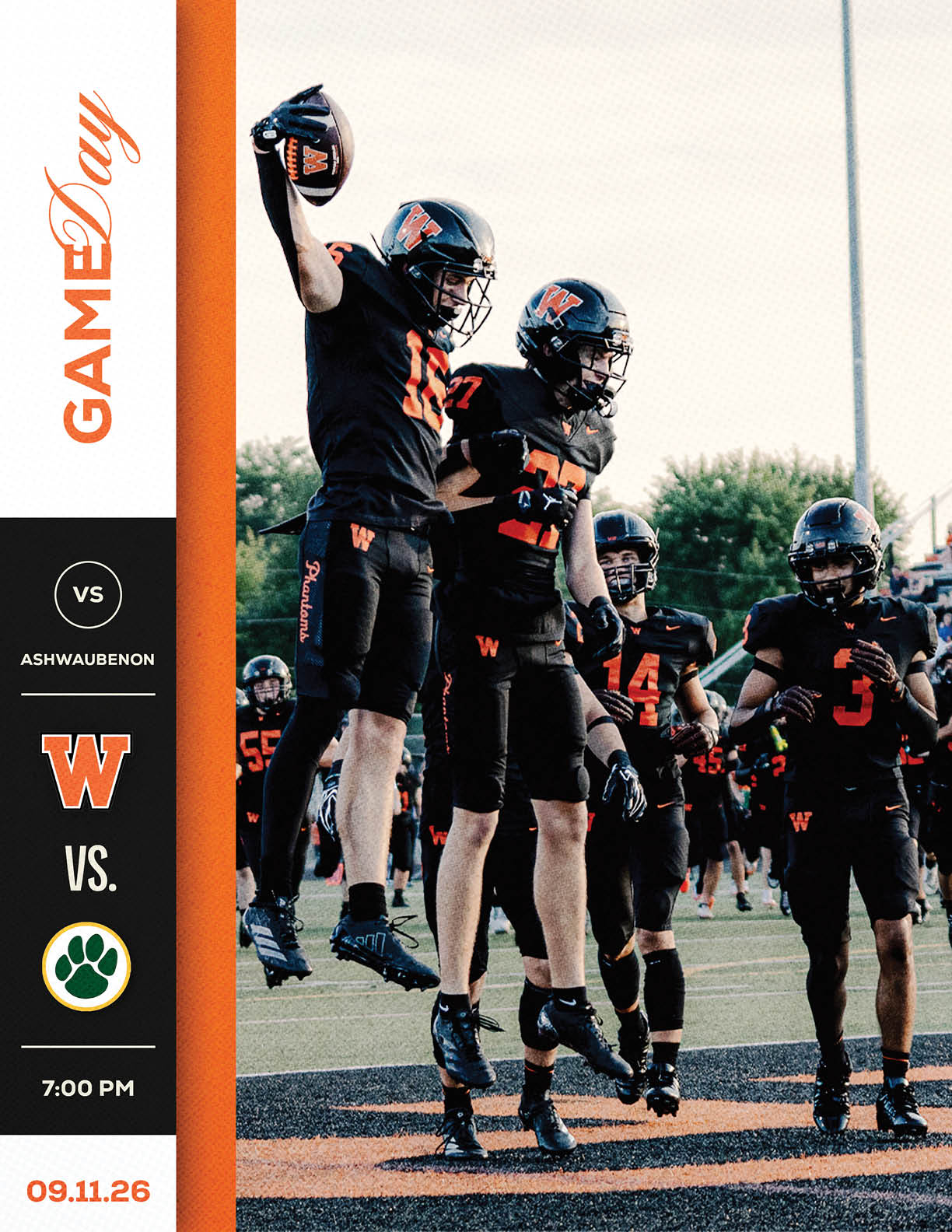A group of football players in black and orange uniforms celebrate on a field with one player jumping and holding a football while others stand nearby. Description generated by AI