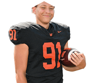 A person wearing a black football uniform with the number 91 in orange is holding a football and smiling. Description generated by AI