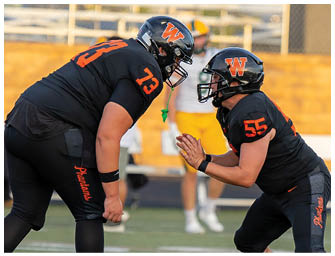 Two people wearing sports attire are on a field, one with “Phantoms" written on their shorts and the other clapping their hands. Description generated by AI