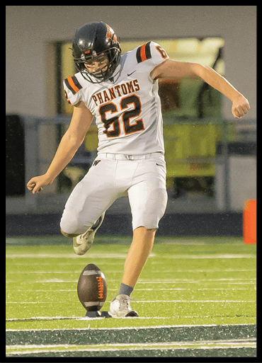 A person wearing a football uniform with the number 62 is in the motion of kicking a football on a field. Description generated by AI