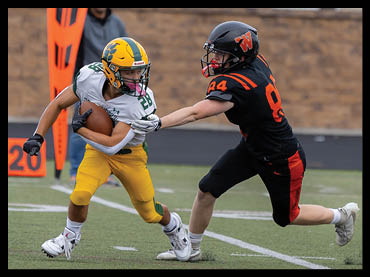 Two people in football uniforms are engaged in a play on a field, with one person in yellow and green holding the ball while the other in black and orange attempts to tackle. Description generated by AI