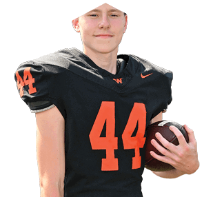 A person wearing a black football uniform with the number 44 in orange is holding a football and smiling slightly. Description generated by AI