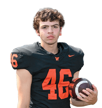 A person with curly hair wearing a black football jersey with the number 46 in orange is holding a football. Description generated by AI