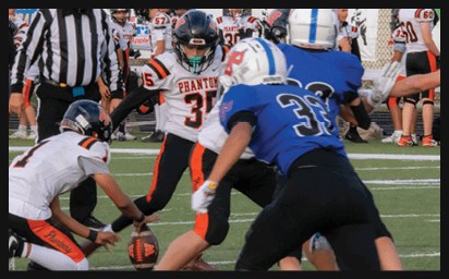 People in football uniforms are actively engaged in a play on a field with a referee observing nearby. Description generated by AI