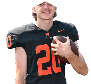 A person wearing a black football jersey with the number 20 in orange is holding a football and smiling. Description generated by AI
