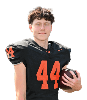 A person wearing a black football uniform with the number 44 in orange is holding a football and smiling slightly. Description generated by AI