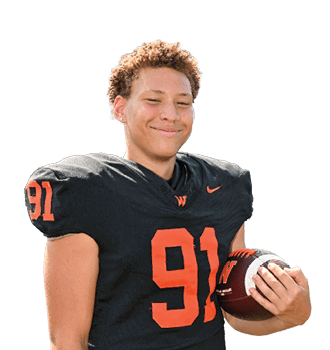 A person wearing a black football jersey with the number 91 is smiling and holding a football. Description generated by AI