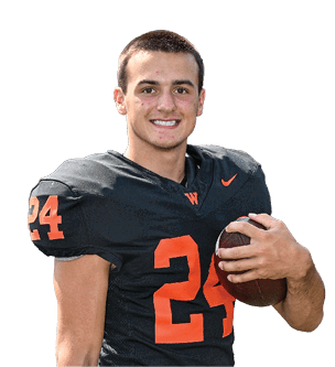 A person wearing a black football jersey with the number 24 in orange is holding a football and smiling. Description generated by AI
